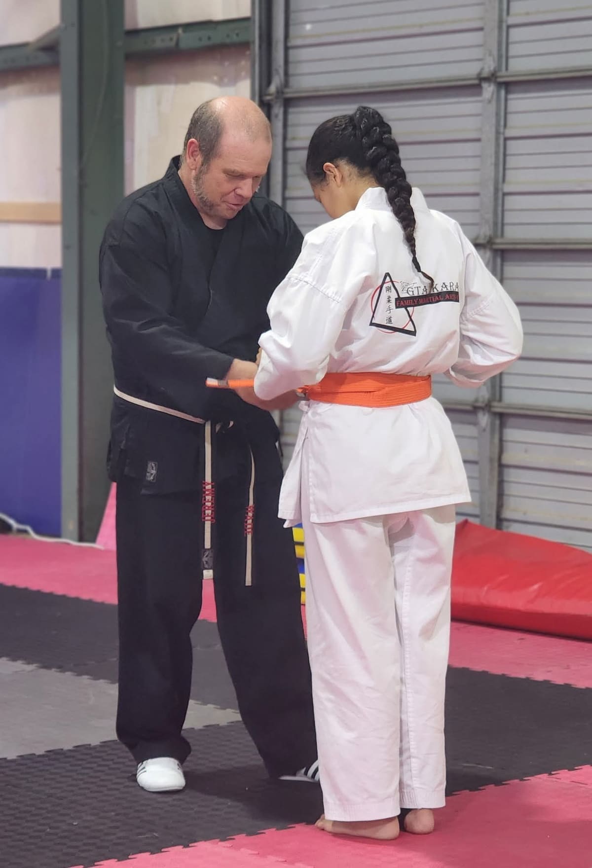 Jeremy tying a new belt on a student at the dojo.